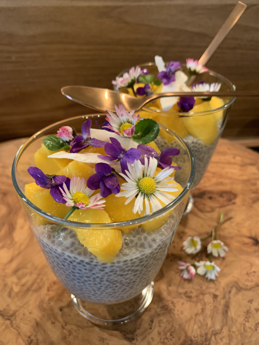 Zwei Gläser mit Chia-Pudding mit Mango und Blüten