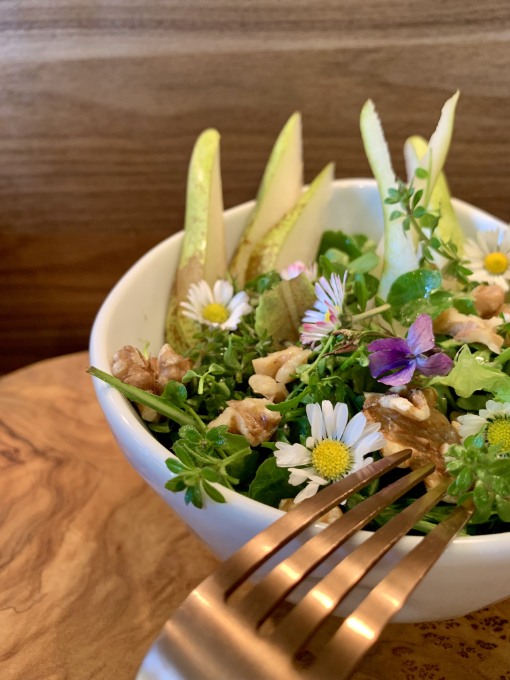 Wildkräuter-Birnensalat in einer Schale und goldener Gabel